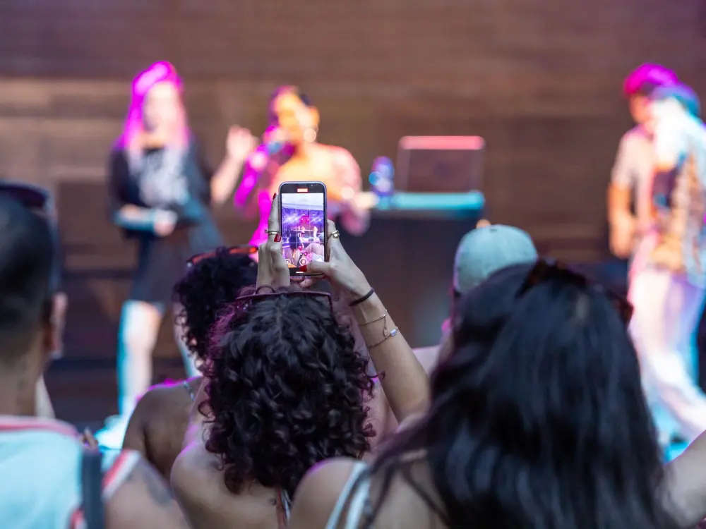 Chovo: Eine Person steht vorne an der Kultursommer-Bühne und filmt mit ihrem Smartphone den Auftritt von Chovo mit.