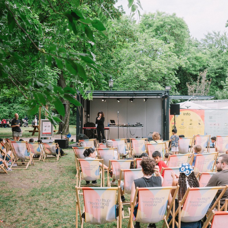KVSAL: KVSAL performt bei der Kultursommer-Bühne im Waldmüllerpark. Menschen sitzen in Liegestühlen vor der Bühne. 