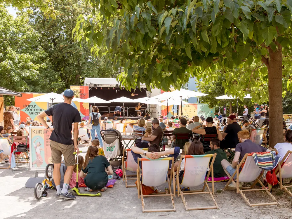 Duo Alone perfomen im Reithofferpark. Es sehen viele Zuschauer:innen zu. 