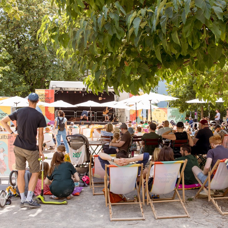 Duo Alone perfomen im Reithofferpark. Es sehen viele Zuschauer:innen zu. 