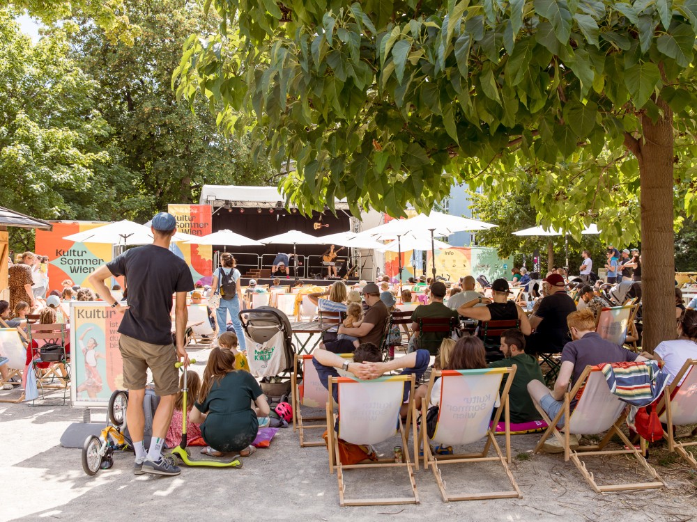 Duo Alone perfomen im Reithofferpark. Es sehen viele Zuschauer:innen zu. 