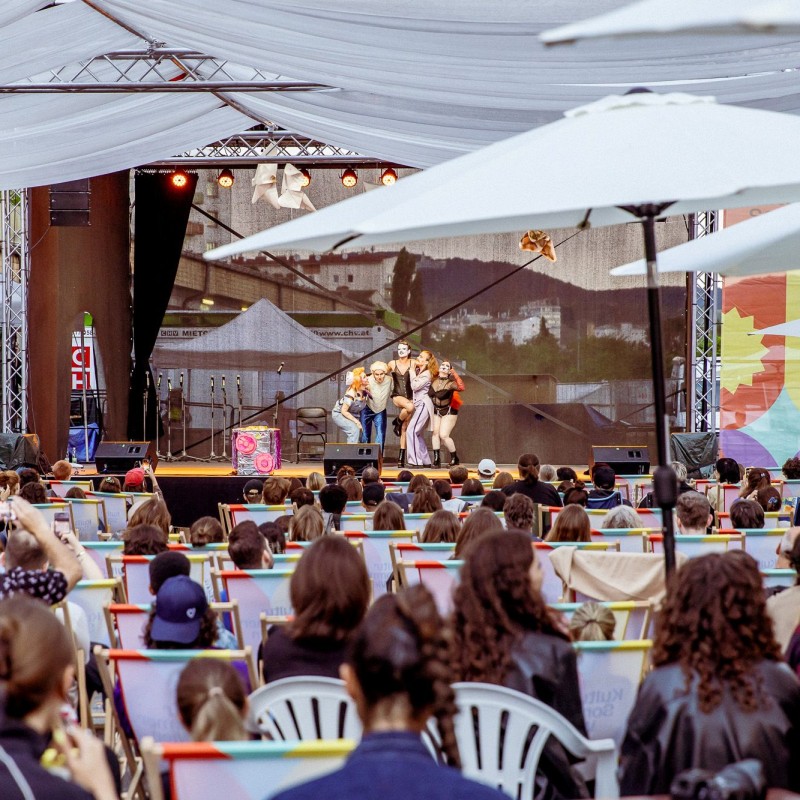 Foto: Judith Stehlik House of Clits performen auf der Kultursommer-Bühne beim Nordwestbahnhof. Über einen Teil des Publikums spannt sich ein Windsegel. Es sind viele Leute anwesend. 