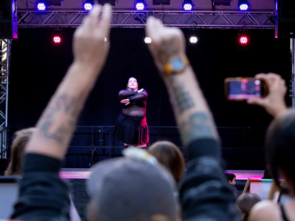 Moschino Squad: Eine Person von Moschino Squad performt auf der Bühne des Kultursommer Wien. Sie hat die Arme in einer tänzerischen Pose um ihren Oberkörper geschlungen.