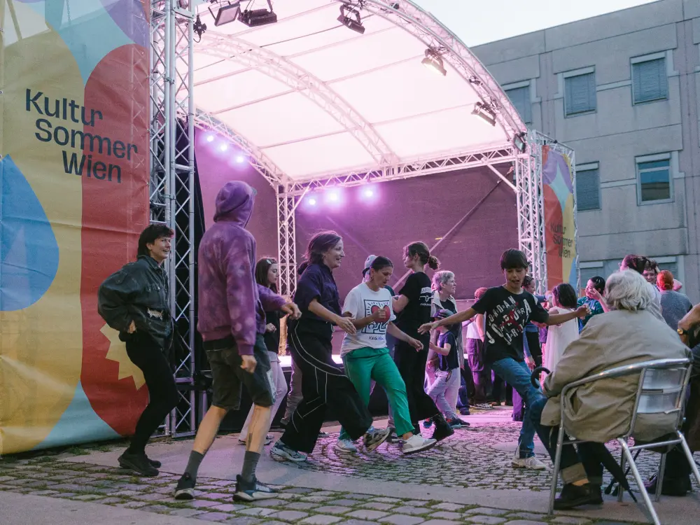 Eine Gruppe Menschen tanzt vor der Kultursommerbühne. 