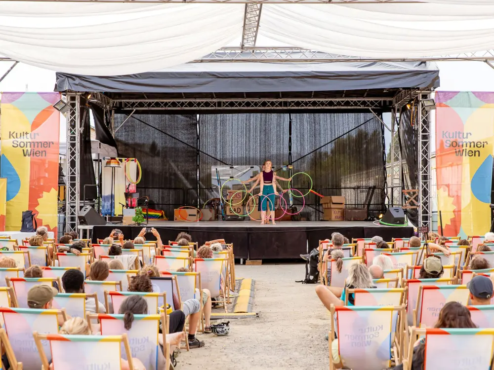 Spinning Tales: Spinning Tales steht auf der Kultursommer-Bühne am Nordwestbahnhof. Mit Hula-Hoop-Reifen bilden die Gruppe einen Halbkreis.