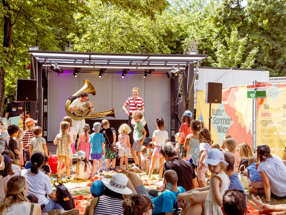 Karin Meissl und Markus Nimmervoll performen beim Kinderfest im Waldmüllerpark. Sie spielen unter anderem auf einer Tuba. 
