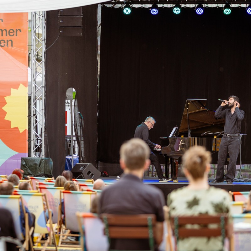 Foto: Judith Stehlik Marino Formenti & Enes Özmen performen auf der Kultursommer-Bühne am Nordwestbahnhof. Marino Formenti spielt auf einem Flügel, Enes Özmen singt ins Mikrofon. 