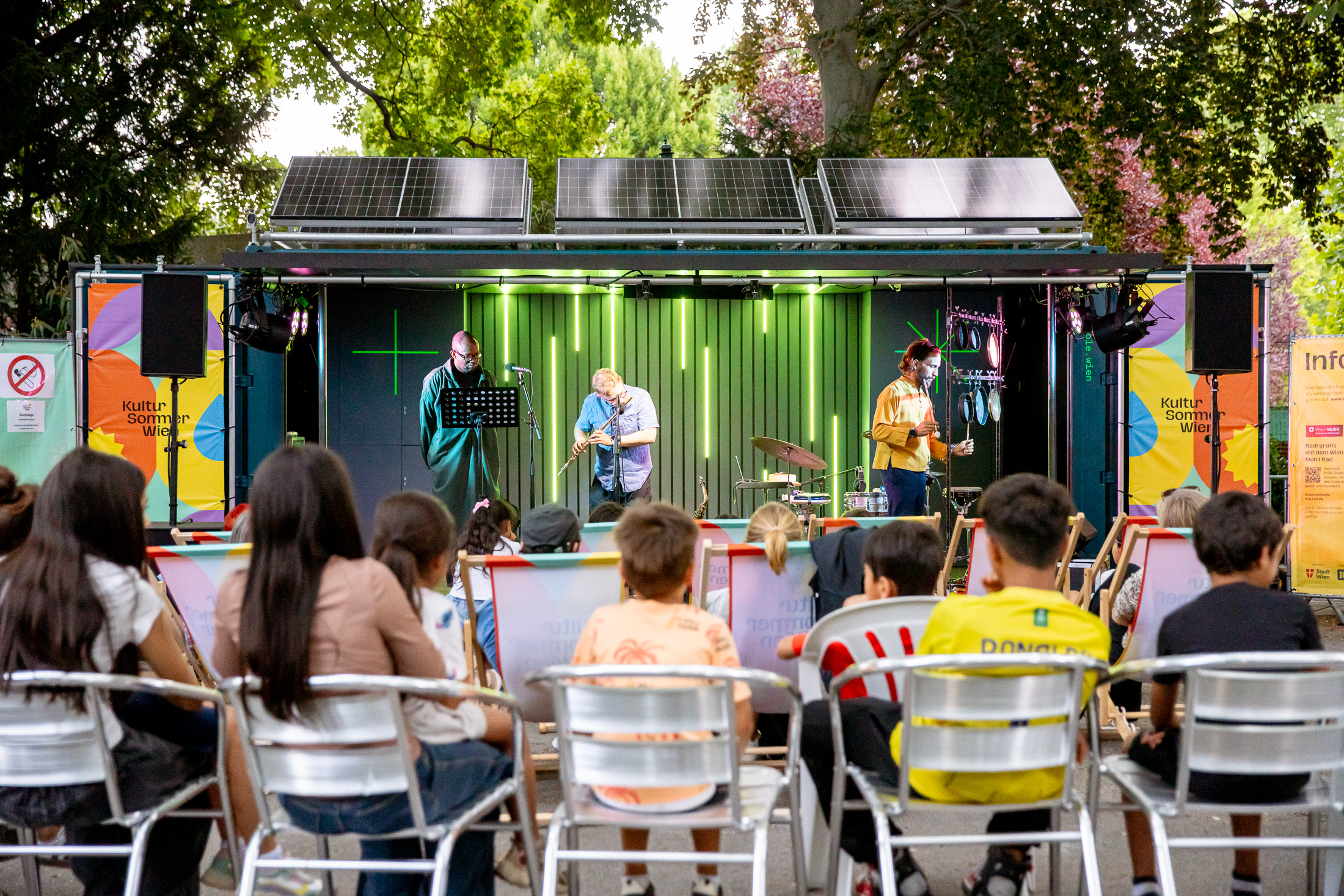 Bender Schulz & Fiston Mwanza Mujila spielen im Kongreßpark beim Kultursommer Wen. Jugendlichen sitzen auf Stühlen vor der Bühne.